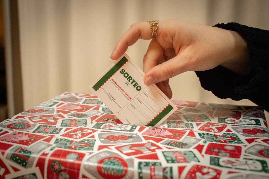 Una mano introduce una papeleta en la urna del sorteo benéfico